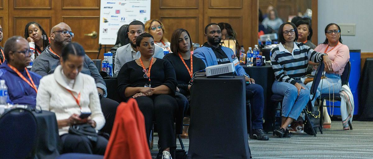 A full room of attendees seated and listening during a general session.