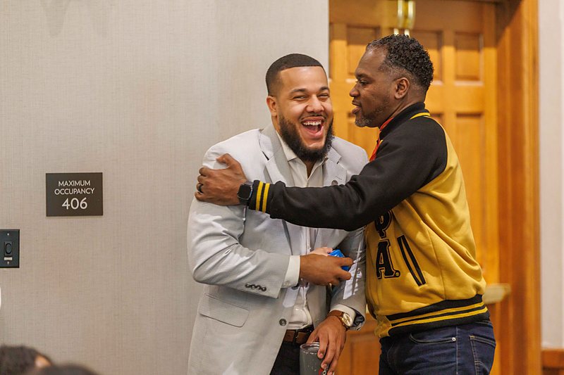 Two attendees greet each other warmly with a hug between sessions.