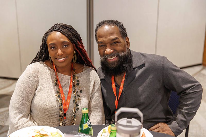 Two attendees sitting together over a meal, talking and smiling.